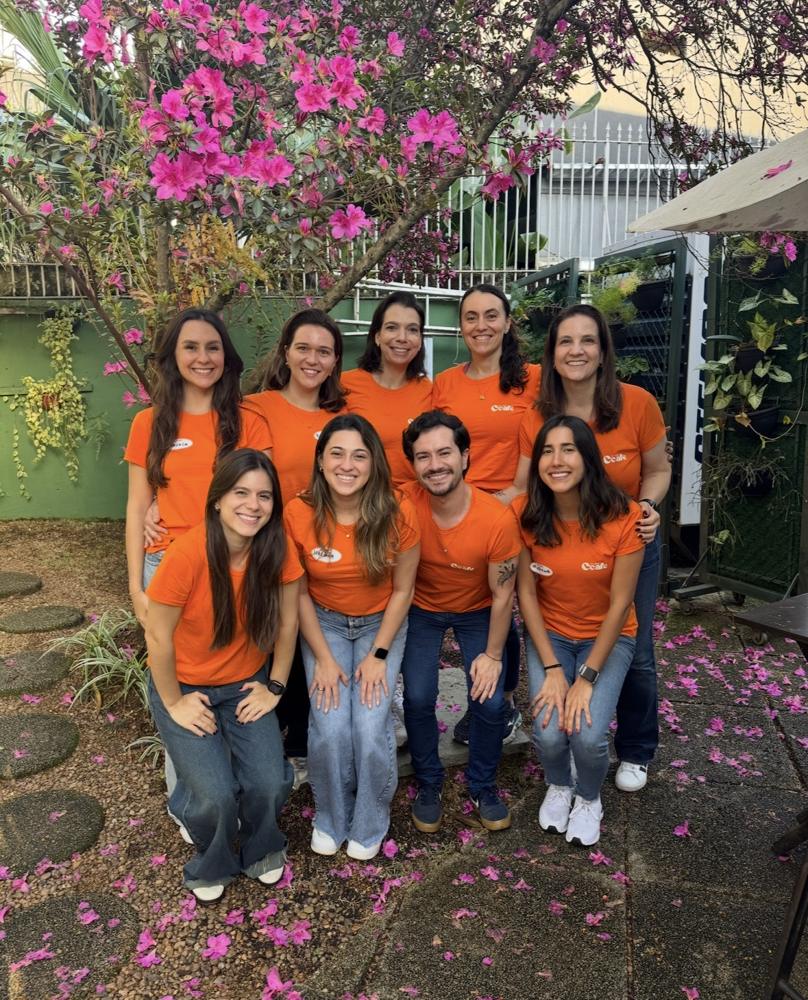Equipe do Clube CCAFE com camisetas laranja em um jardim florido